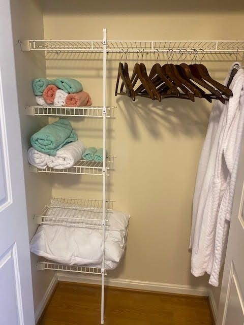 A neatly organized closet with towels, robes, and hangers.