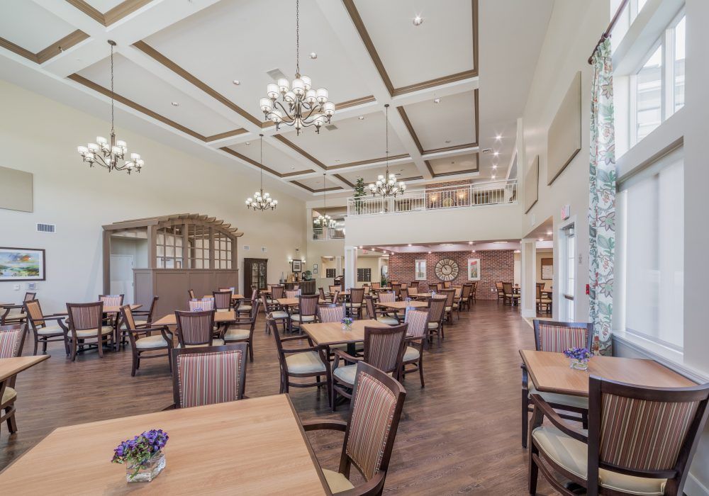 A spacious and elegantly designed dining area with chandeliers and arranged tables.