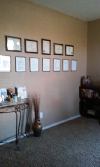 A neatly decorated office corner with framed wall art and a small console table.