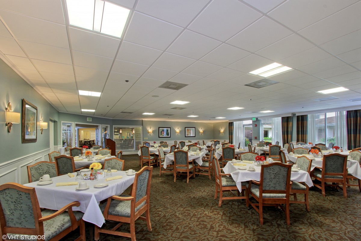 A spacious dining area with neatly arranged tables and chairs under bright lighting.