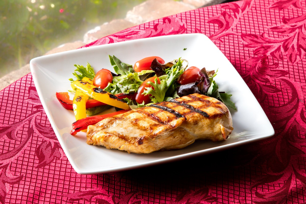 A delicious plate of grilled chicken served with a fresh and colorful salad.