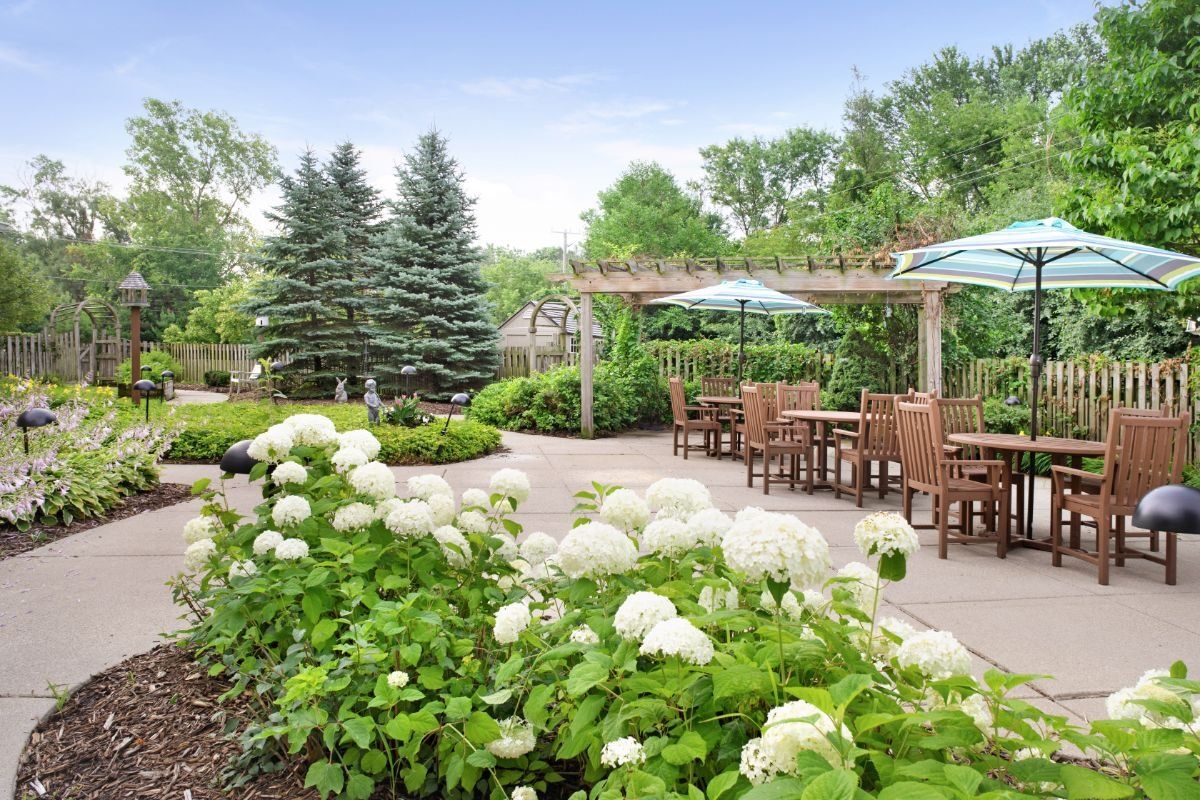 A beautifully landscaped garden patio with outdoor seating, blooming hydrangeas, and a pergola.