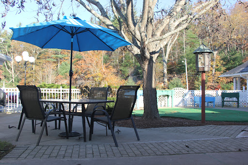 A serene outdoor patio setup with a blue umbrella, surrounded by trees and scenic views.