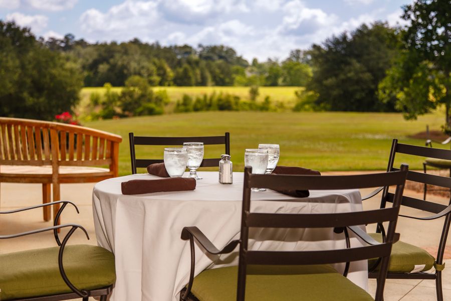 A serene outdoor dining area set with a table and chairs overlooking a lush, green landscape.