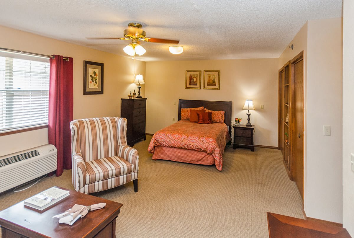 A cozy bedroom with a comfortable bed, armchair, and warm lighting.