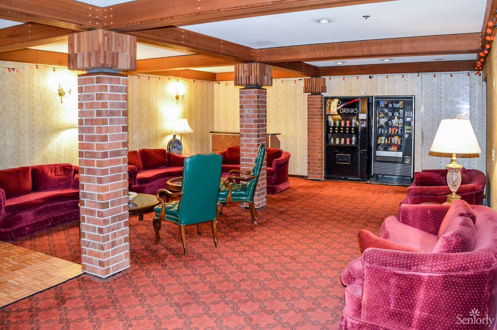 A cozy lobby area featuring vibrant furniture and exposed brick columns with vending machines in the background.