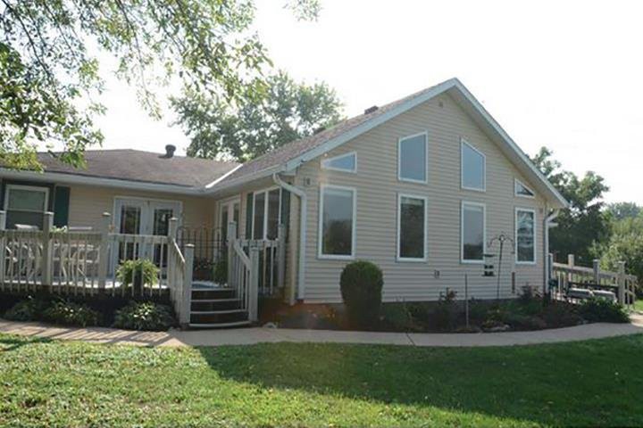 A suburban single-story house with a well-maintained yard and large windows.