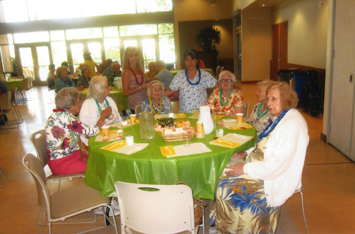A group of elderly people enjoying a social gathering around a dining table.