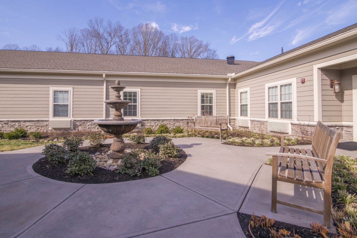 A peaceful courtyard with a central fountain, surrounded by landscaping and benches.