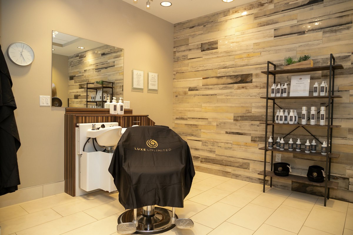 A modern hair salon with a barber chair, stylish wood paneling, and shelves filled with hair products.