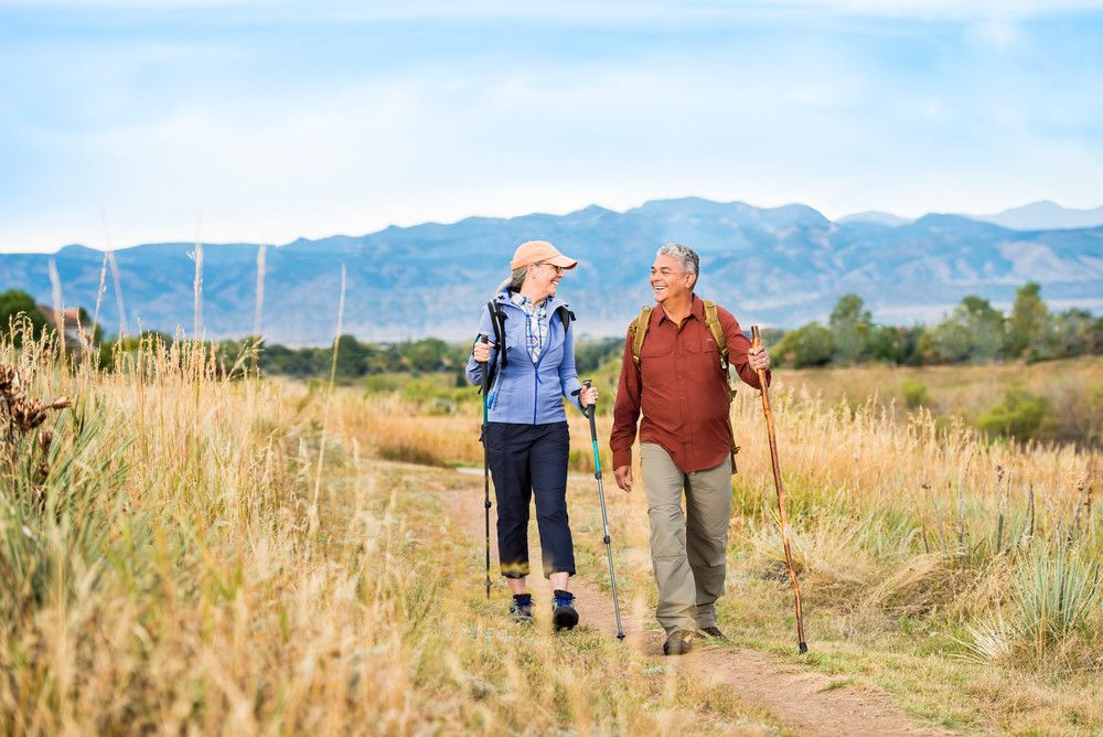 A couple enjoying a hike on a scenic trail with mountains in the background.