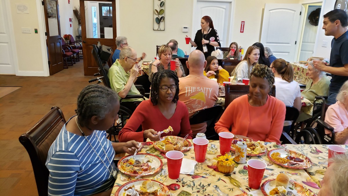 A diverse group of people enjoying a shared meal indoors, engaging in conversation and dining together.