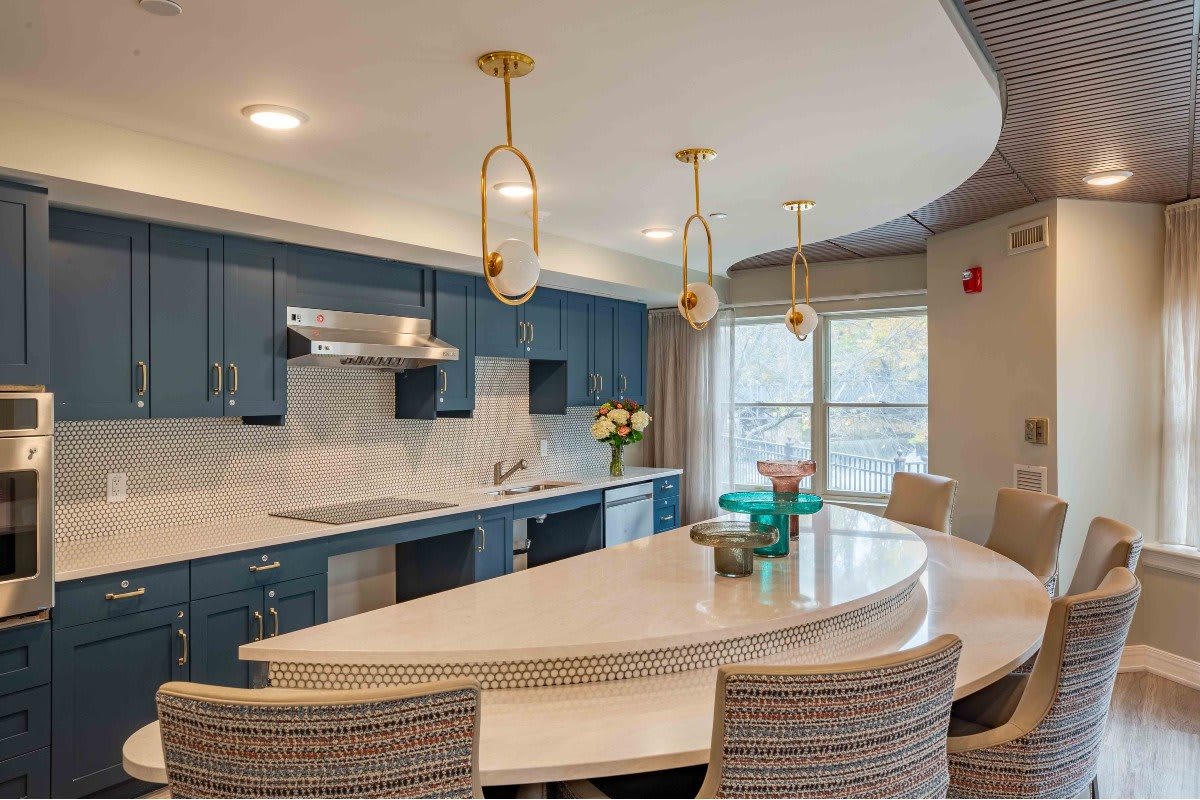 A modern kitchen with blue cabinets, a large island, and stylish pendant lighting.