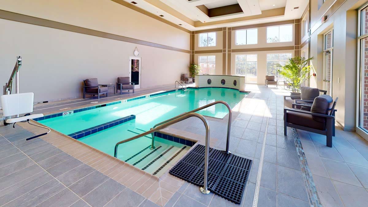 An elegant indoor swimming pool with ample natural lighting and comfortable seating.