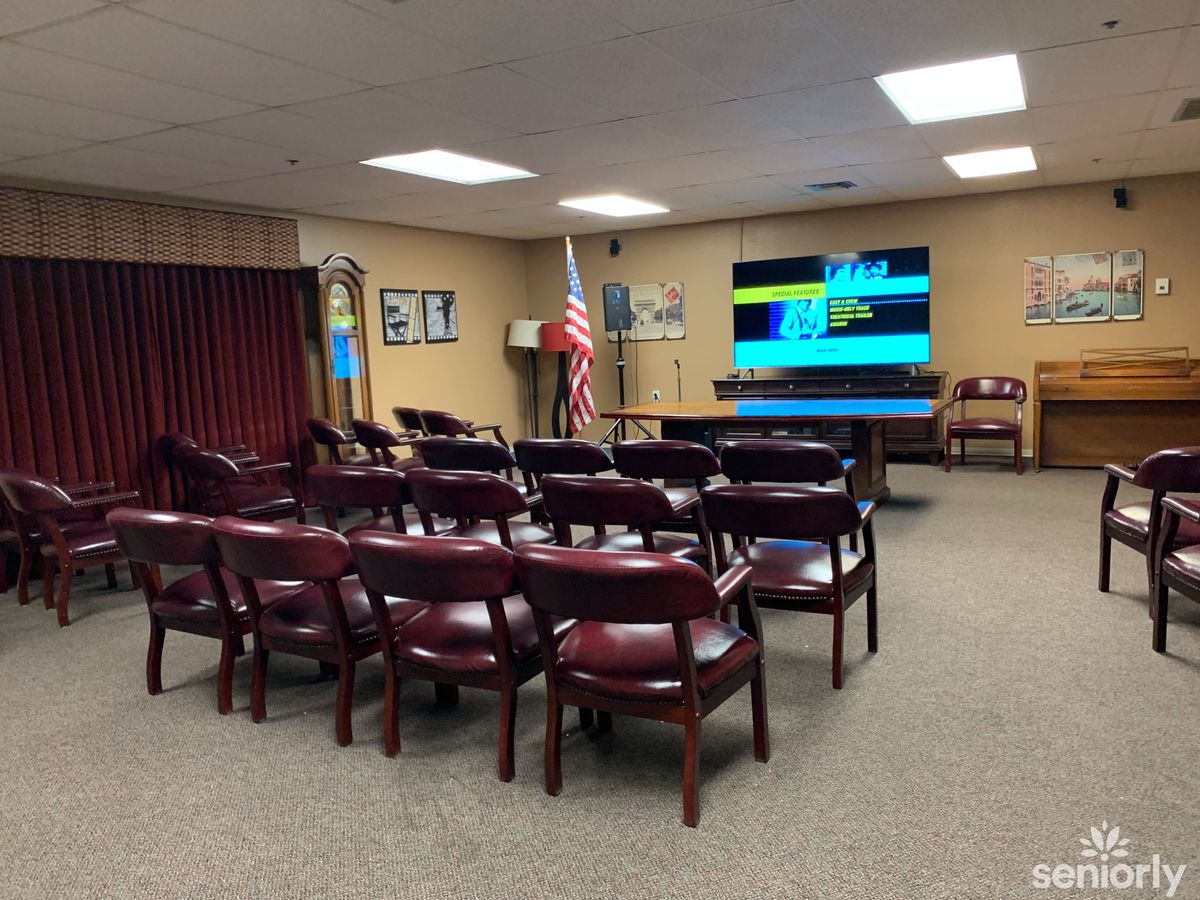 A meeting room with rows of chairs facing a projector screen and an American flag in the corner.