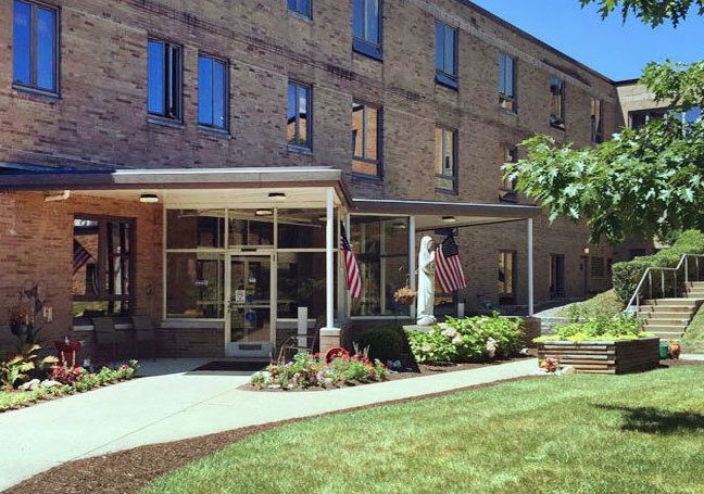 Entrance of a brick building with flags and well-maintained landscaping.