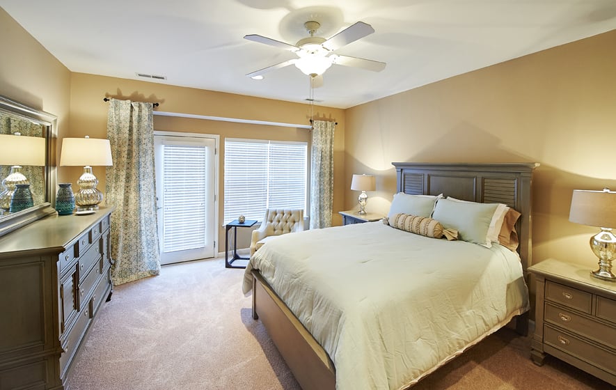 A cozy bedroom with a double bed, ceiling fan, and natural light streaming through the windows.