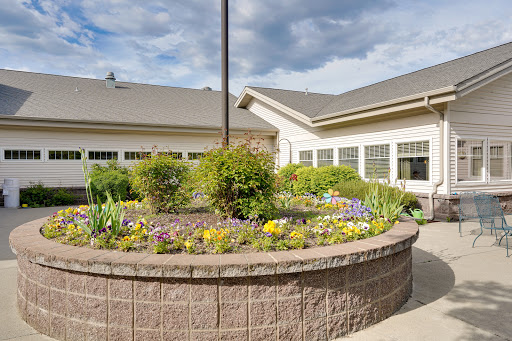 A beautifully landscaped garden featuring a circular flower bed, surrounded by a modern building.