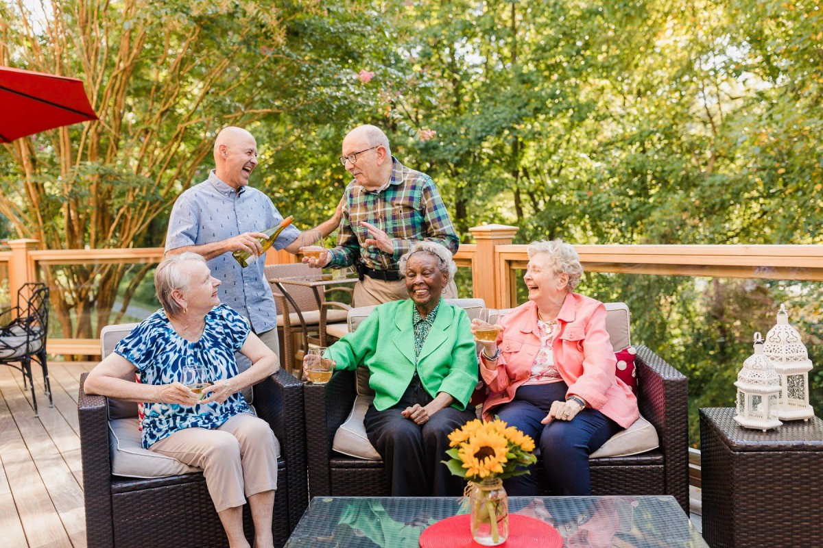 A group of elderly friends enjoying a conversation outdoors on a sunny day.