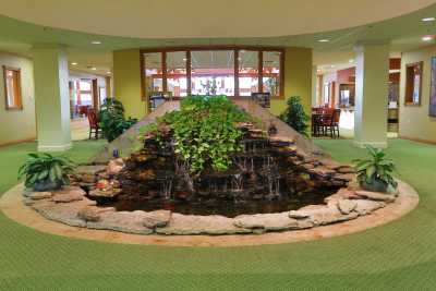 An indoor lobby featuring a decorative water fountain surrounded by plants.
