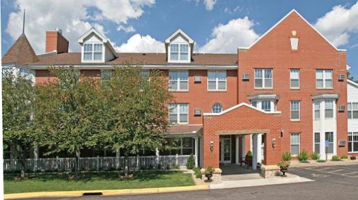 A view of a three-story brick hotel with a welcoming entrance under a partly cloudy sky.