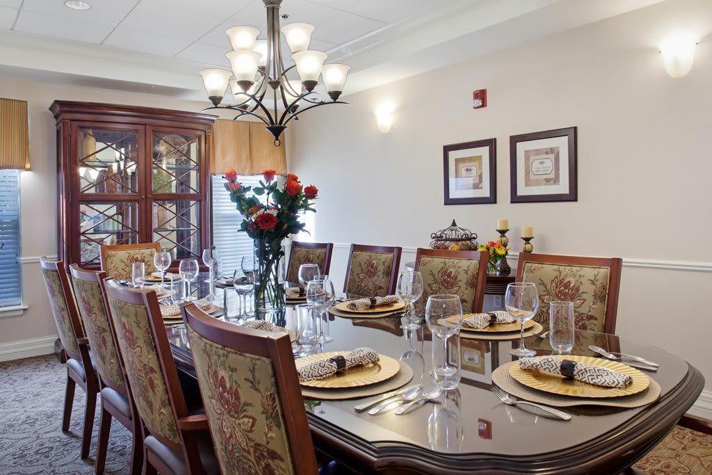 A beautifully set dining room table with elegant decor and a chandelier overhead.