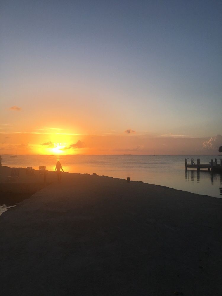 A serene sunset over the ocean with a dock in view.