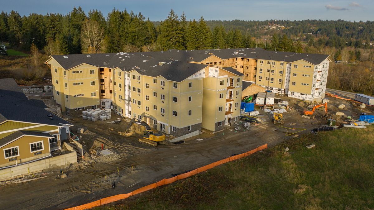 Aerial view of an apartment building under construction surrounded by trees.