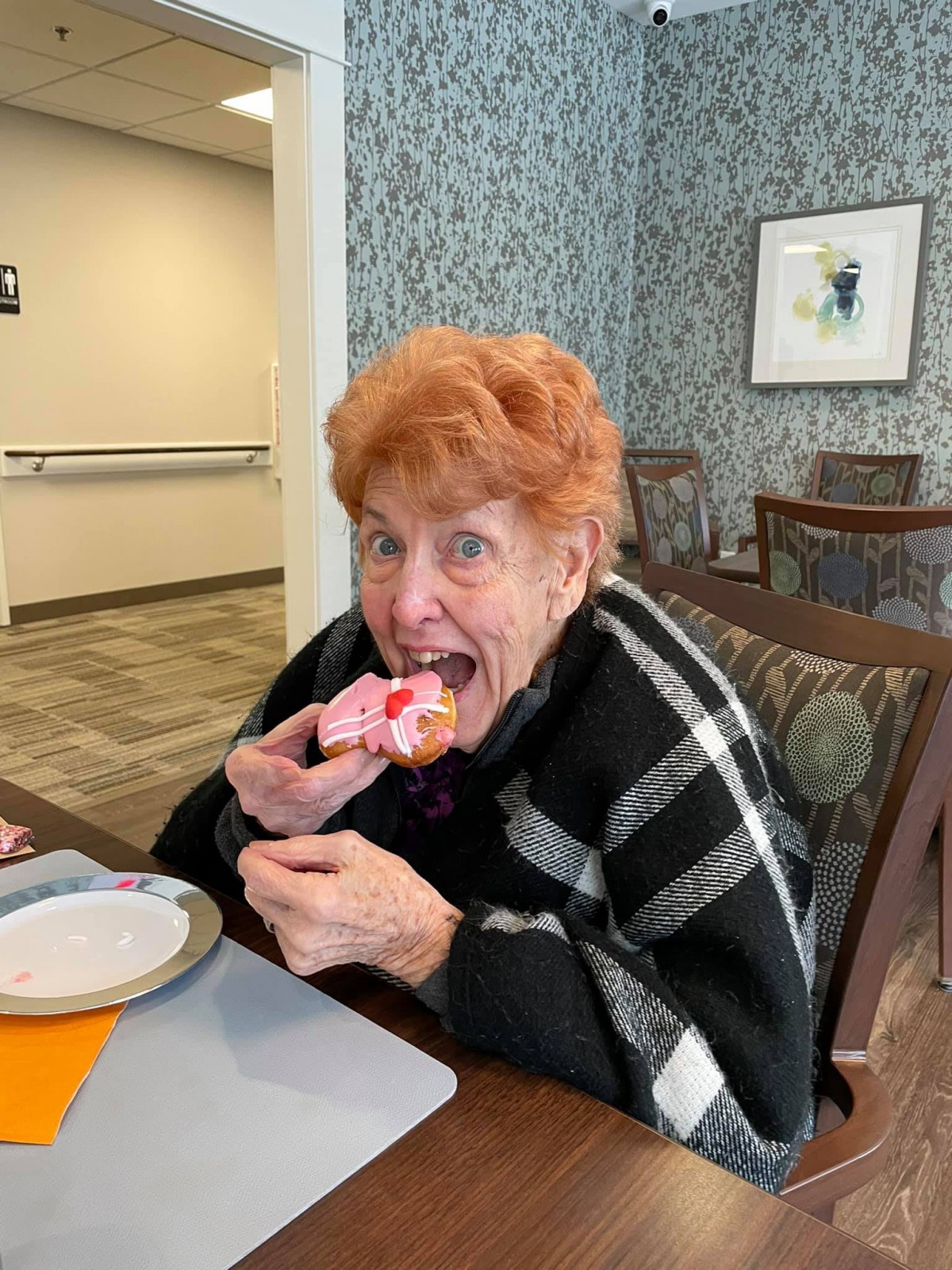 A joyful woman enjoying a dessert at a table indoors.