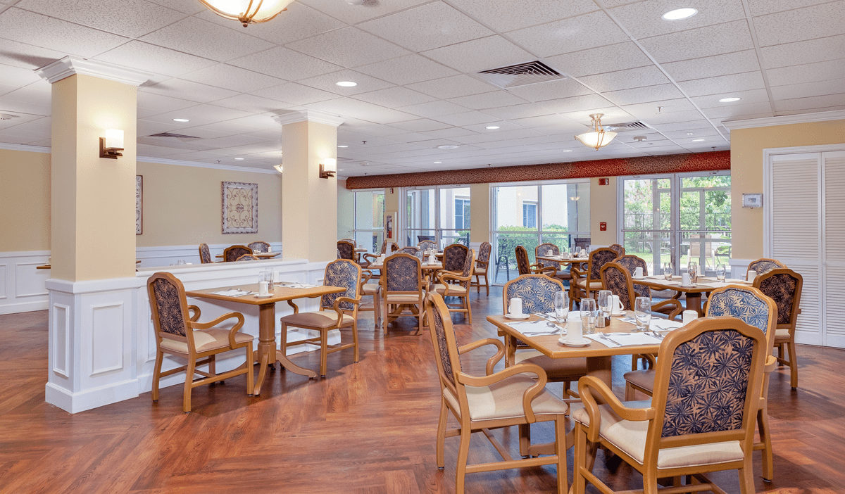 A spacious dining area with wooden tables and chairs, featuring large windows for natural light.