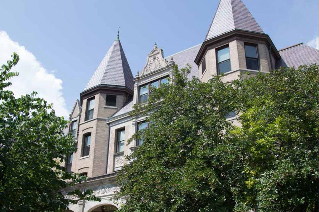 A historical building with towers surrounded by trees under a clear sky.