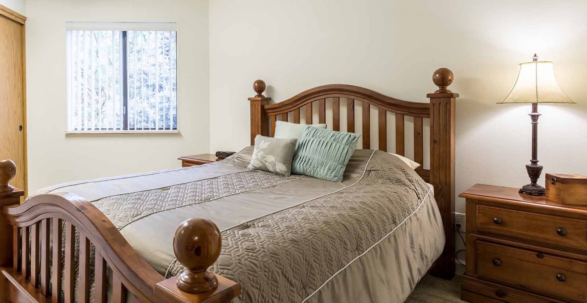 A cozy bedroom featuring a bed with a wooden headboard and decorative pillows.