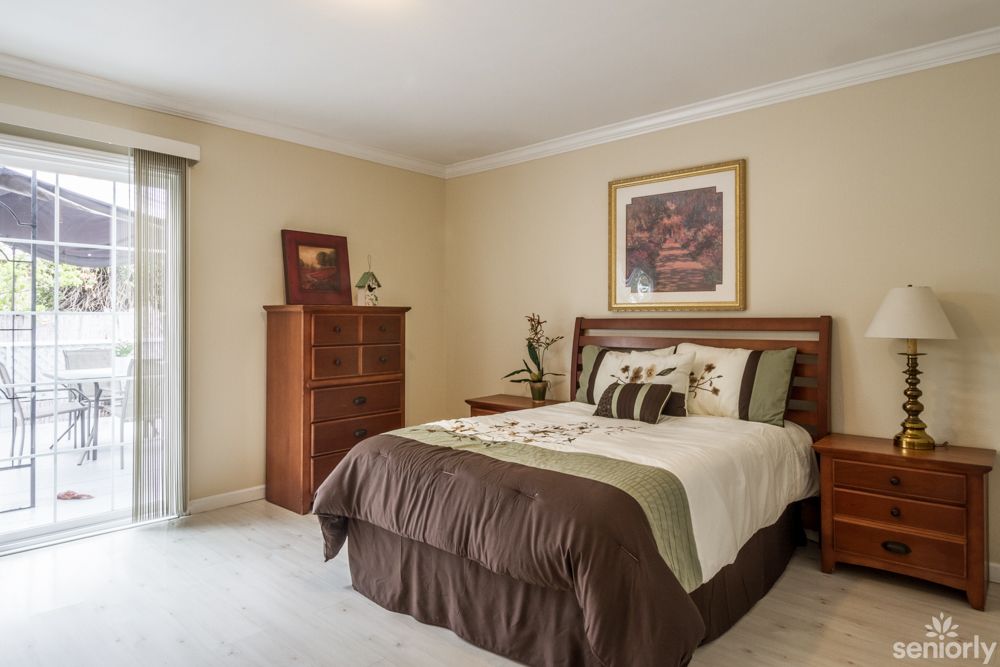 A cozy bedroom featuring a neatly made bed, wooden furniture, and wall decor.