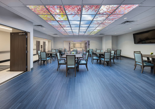 A spacious and well-lit dining area featuring a colorful stained glass ceiling, surrounded by tables and chairs.