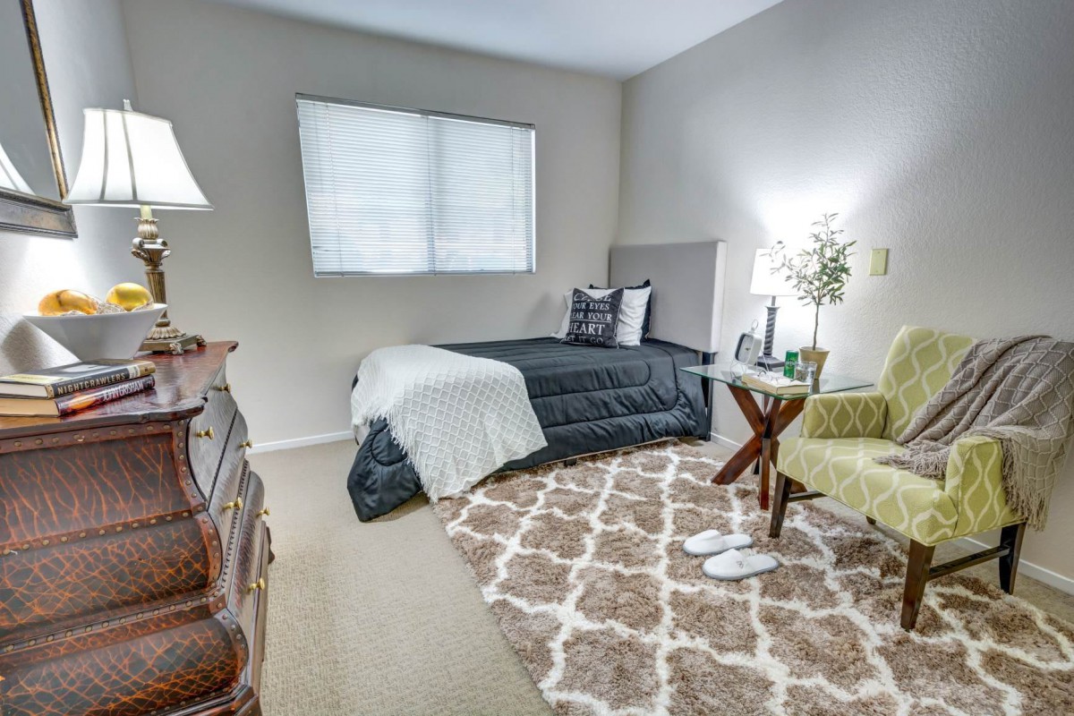 A cozy bedroom with a single bed, patterned rug, and tasteful decor.
