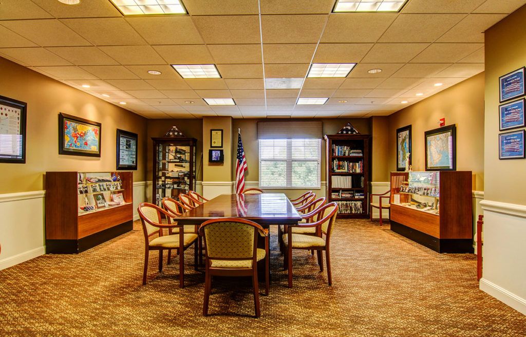 A conference room with a central table, chairs, bookshelves, and decorative elements.