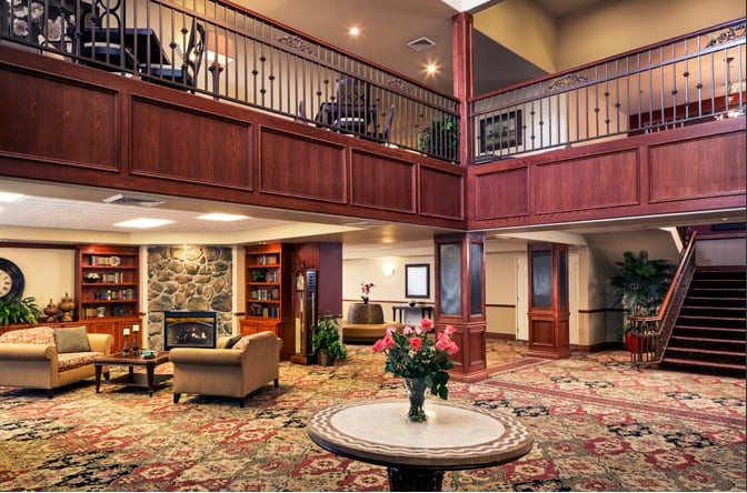A cozy hotel lobby featuring a fireplace, elegant wood paneling, and comfortable seating.