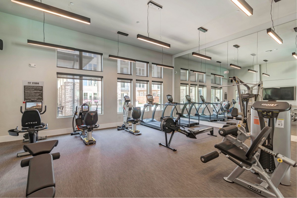 A modern gym with various exercise equipment and large windows.