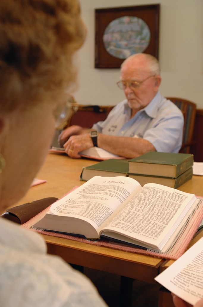 Two individuals engaged in reading and studying books in a library setting.