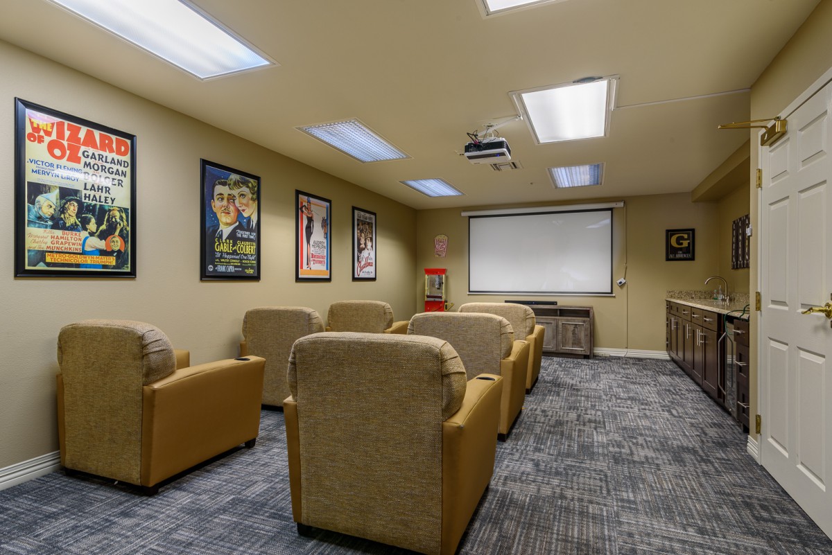 A cozy home theater with comfortable seating and a projector screen, decorated with movie posters.