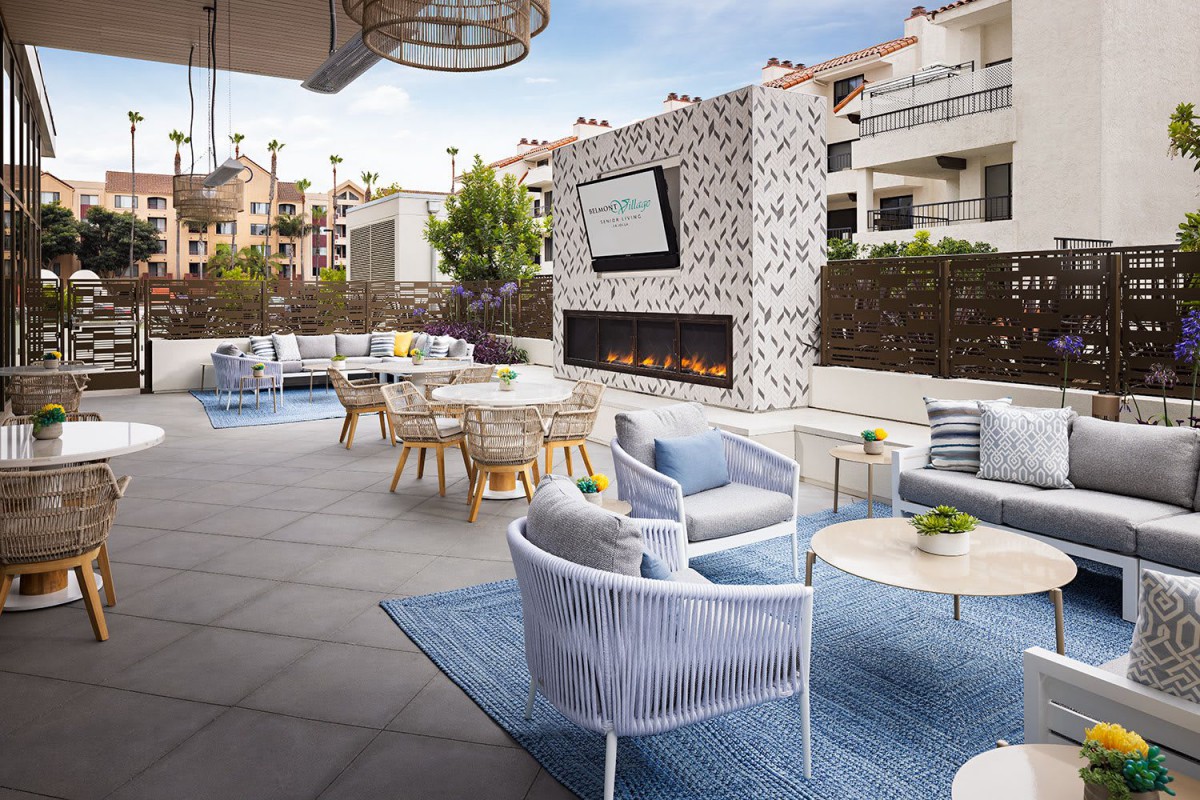 A modern outdoor patio featuring cozy seating arrangements and a large fireplace, perfect for relaxation and entertainment.