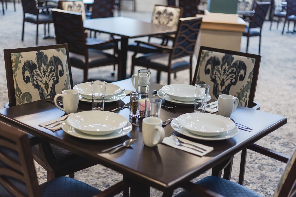 A neatly set dining table in a restaurant with plates, cups, and cutlery.