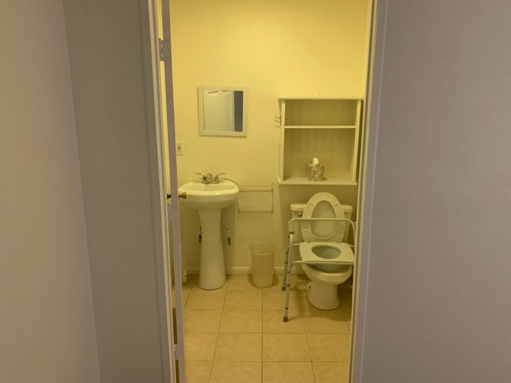 A small bathroom with a sink, toilet, and shelving unit.