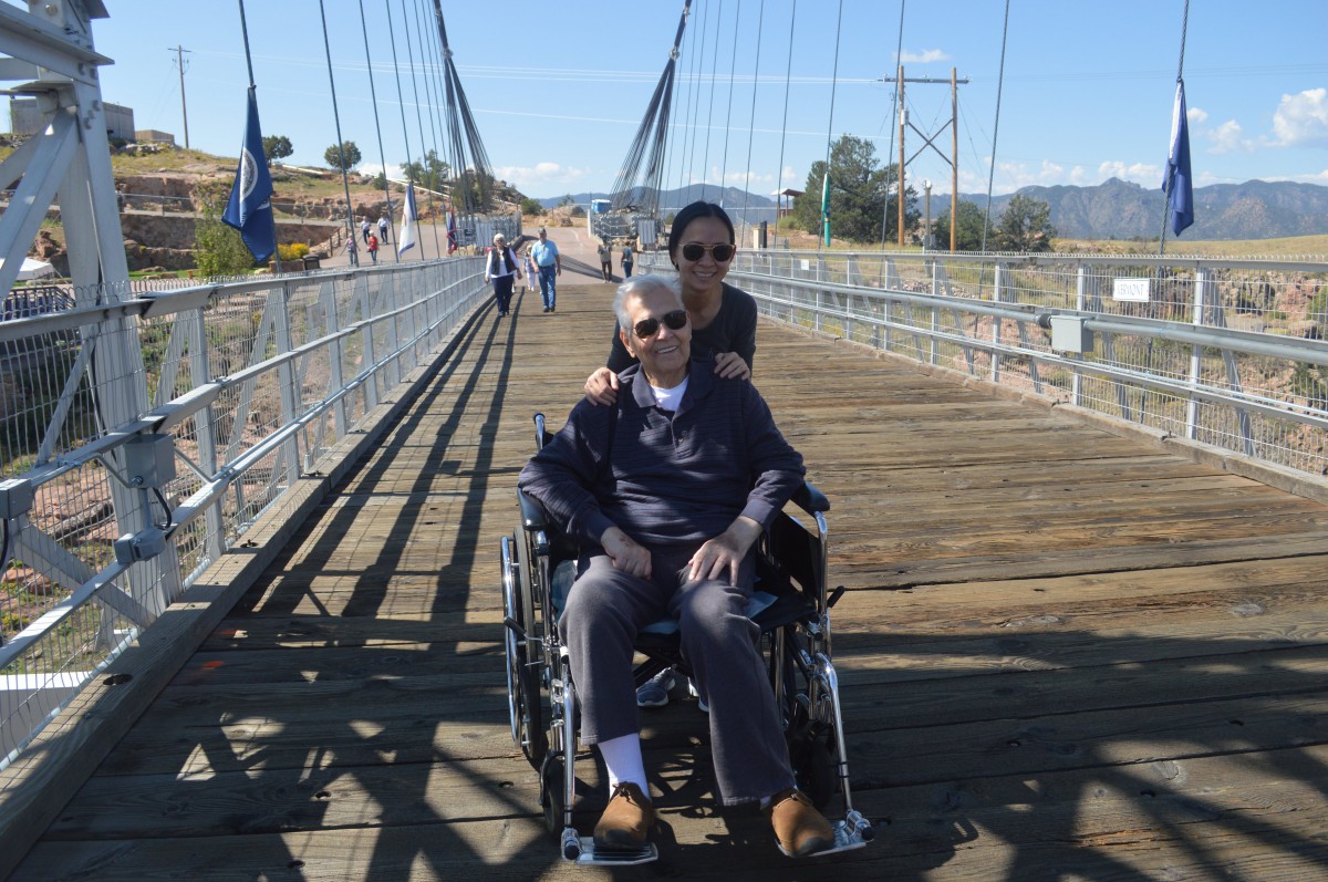 A person in a wheelchair on a bridge, accompanied by another person.