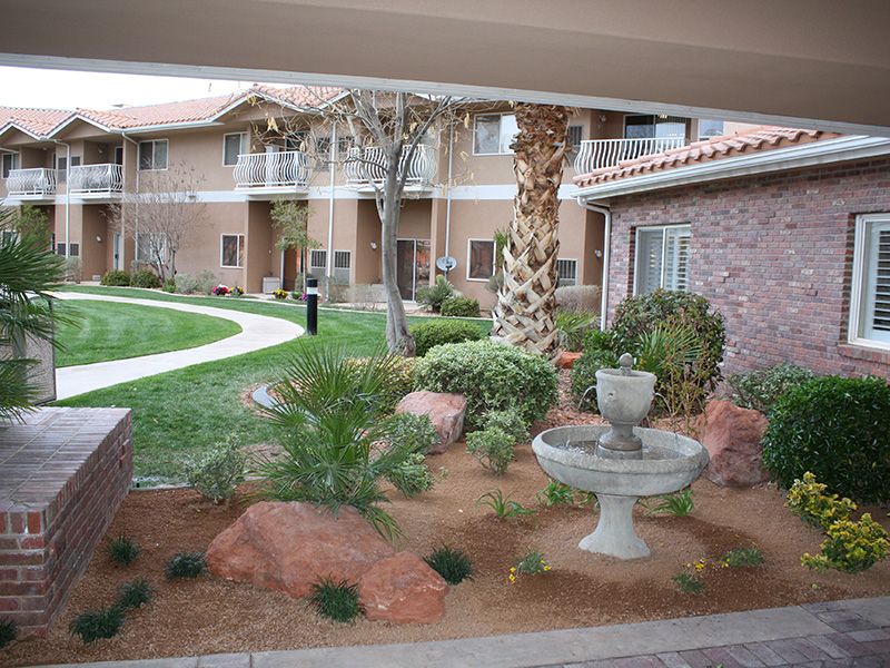 A tranquil courtyard with landscaped greenery and a central fountain, surrounded by residential buildings.