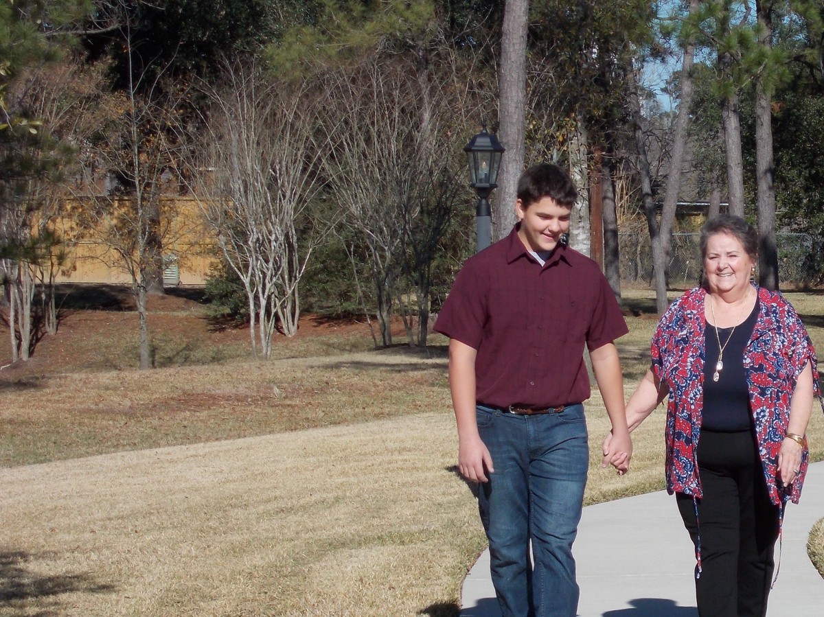A couple walking hand in hand along a park pathway on a sunny day.