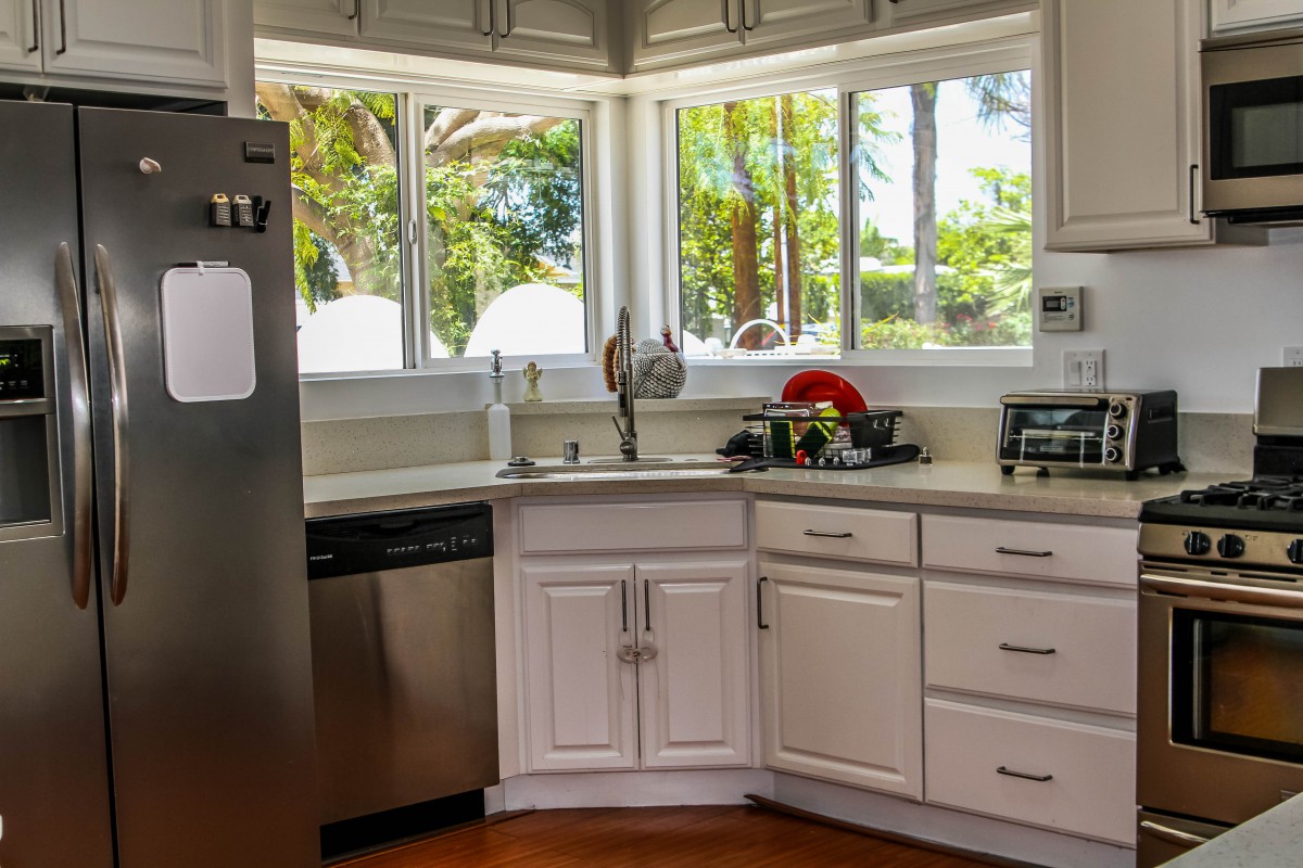 A bright, modern kitchen with white cabinets and large windows.