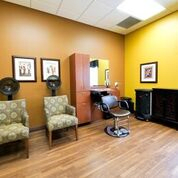 A cozy hair salon with chairs, a mirror, and dryers in a warmly decorated space.