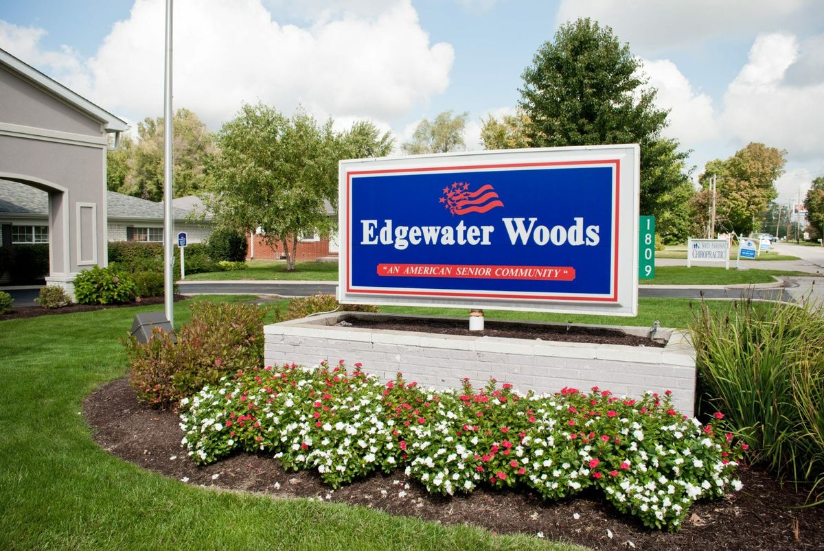 A sign for Edgewater Woods surrounded by a landscaped garden with flowers.