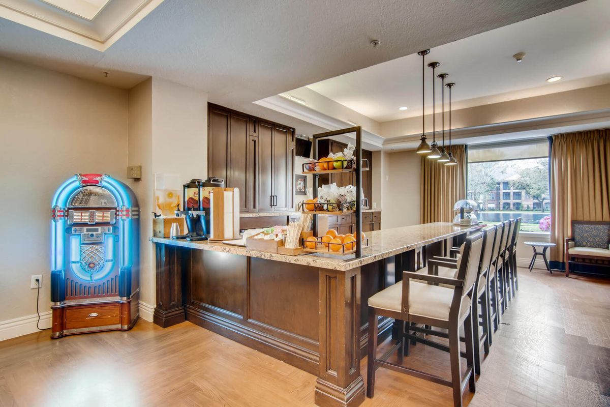 A modern kitchen bar area featuring a countertop with stools, elegant lighting, and a jukebox for entertainment.